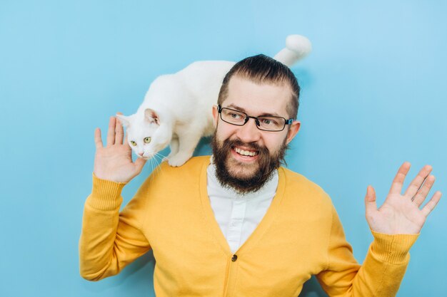 Foto um homem alegre com um gato branco no ombro.