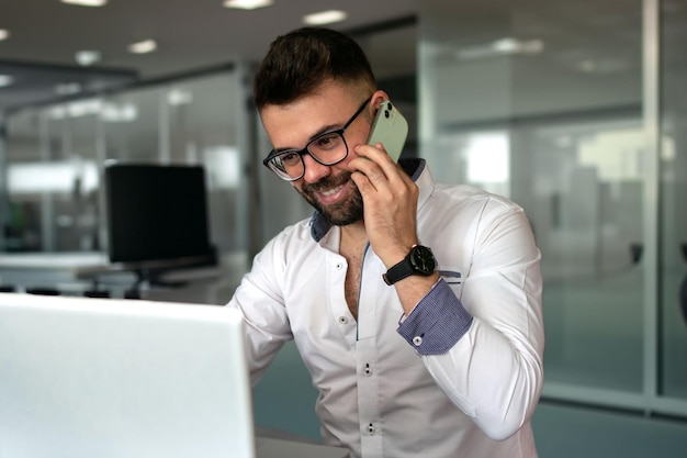 Um homem alegre, profissional de TI, com fones de ouvido bluetooth, a trabalhar à distância e a manter um estilo de vida freelance.