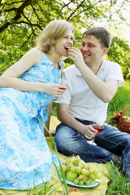 Um homem alimentando uvas para uma mulher de piquenique