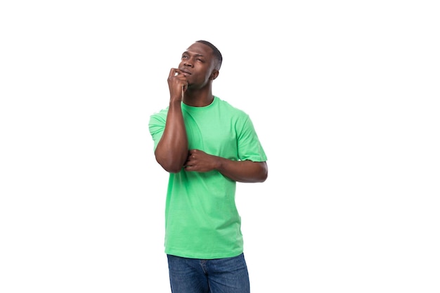 Um homem americano de um ano de idade vestido com uma camiseta básica verde claro olha para cima pensativo