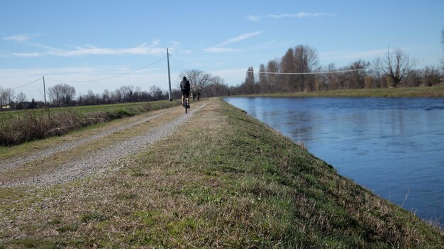 Um homem anda de bicicleta ao longo de um rio na Bélgica.
