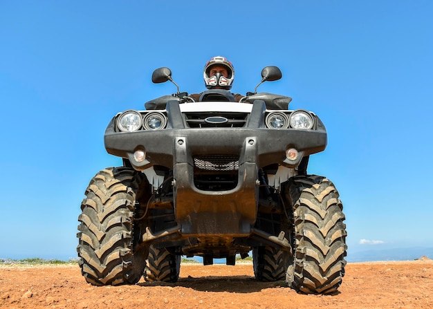 Um homem andando de quadriciclo na areia com capacete protetor