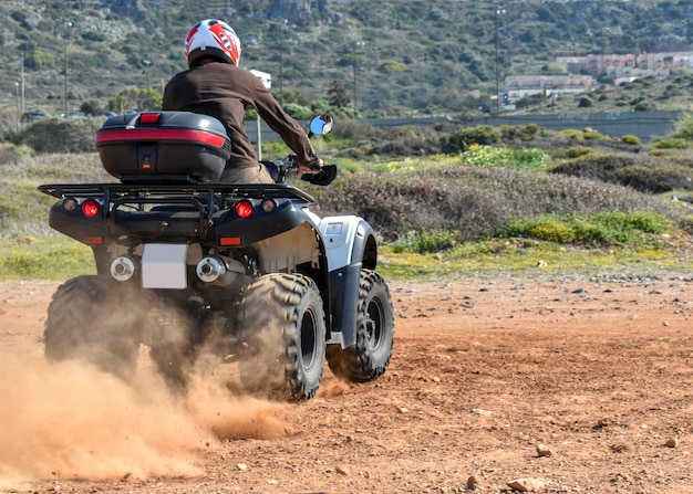 Um homem andando de quadriciclo na areia com capacete protetor