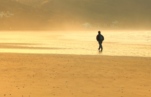 Um homem andando sozinho na praia
