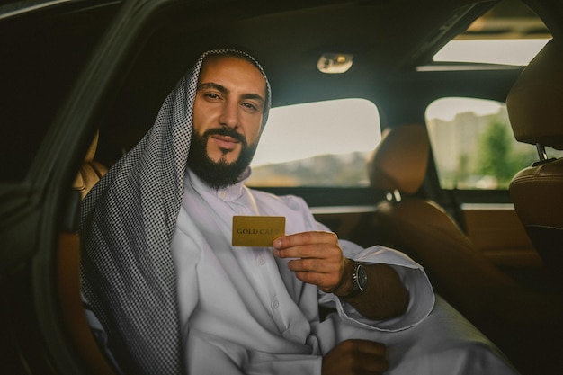 Um homem árabe em uma roupa tradicional em um carro segurando um cartão de crédito