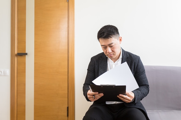 Um homem asiático à espera de uma entrevista de emprego na sala de espera do centro de escritórios