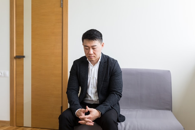 Um homem asiático à espera de uma entrevista de emprego na sala de espera do centro de escritórios