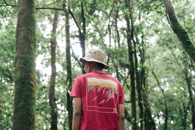 um homem asiático de chapéu em uma floresta tropical