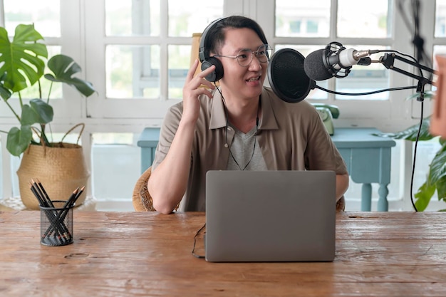 Um homem asiático está usando podcasting de microfone em casa