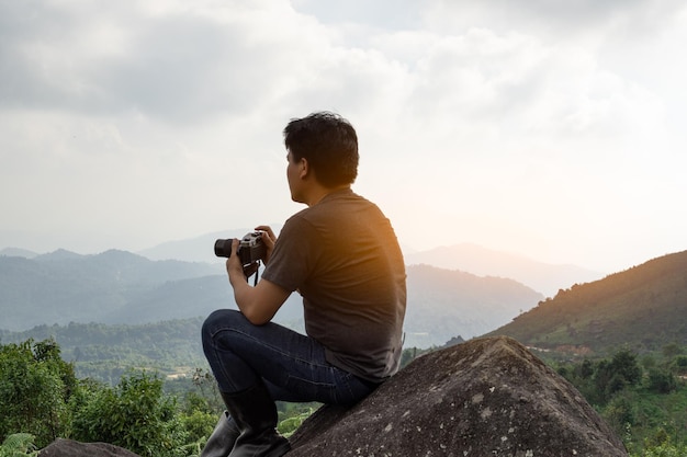 Um homem asiático pegando câmera viajando sozinho na montanha