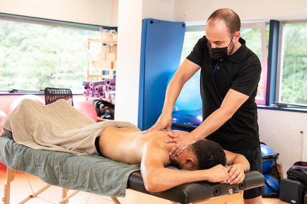 Um homem atlético recebendo uma massagem de recuperação por um fisioterapeuta em uma maca detalhe de massagem terapêutica e osteopatia no mesmo centro esportivo