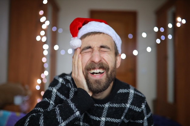 Um homem barbudo com um chapéu de Papai Noel O homem sorri e gosta do retrato de Ano Novo Closeup