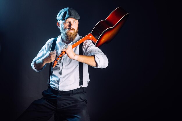 Um homem barbudo de chapéu com guitarra em estúdio