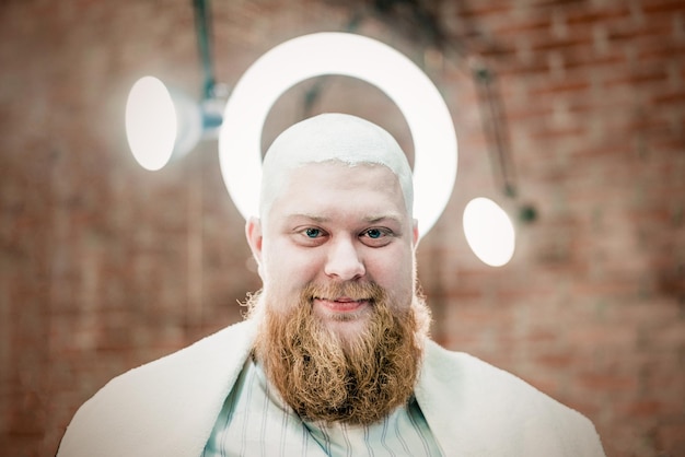 Um homem barbudo ruivo careca com gel de barbear na cabeça