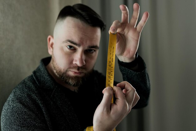 Foto um homem barbudo segura uma fita de um centímetro