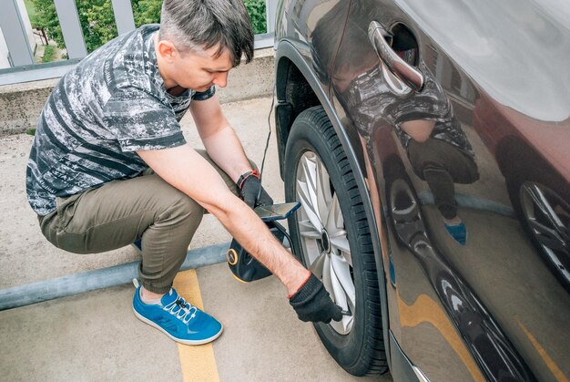 Foto um homem bombeia a roda de um carro com uma bomba no estacionamento