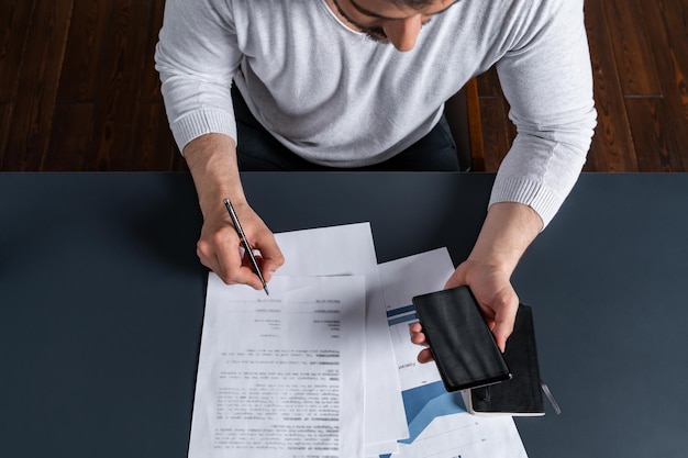 Um homem bonito assinando o contrato verificando os detalhes no celular O conceito de entrar no poder legal para assumir responsabilidades Vestuário casual