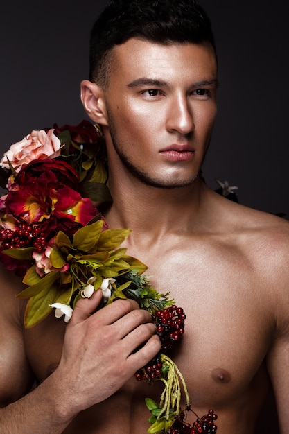 Um homem bonito, com flores no corpo.