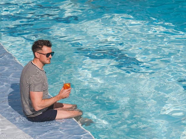 Um homem bonito senta-se perto da piscina