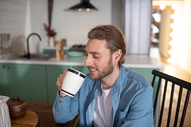 Um homem bonito tomando sua xícara de chá matinal