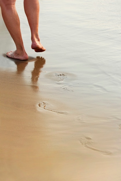 Um homem caminha em uma praia de areia molhada no mar