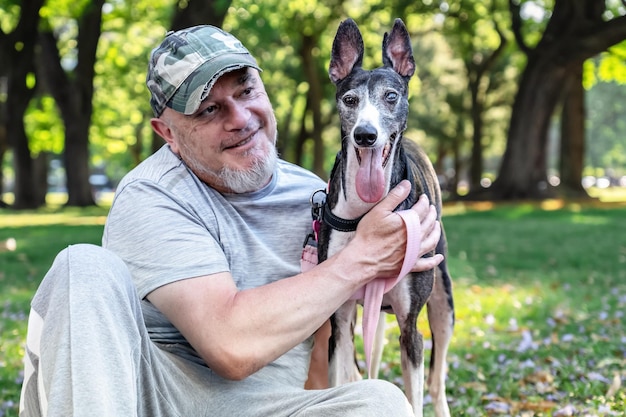 Um homem careca maduro com o seu galgo