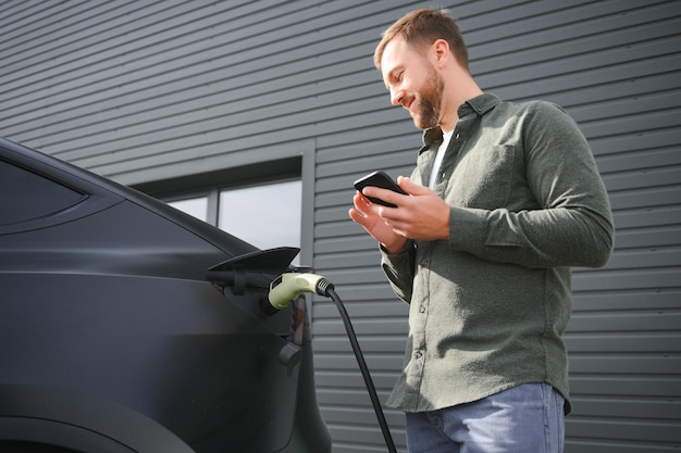 Um homem carrega o seu carro elétrico moderno O conceito de energia verde