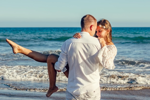 Um homem carregando uma mulher em uma praia