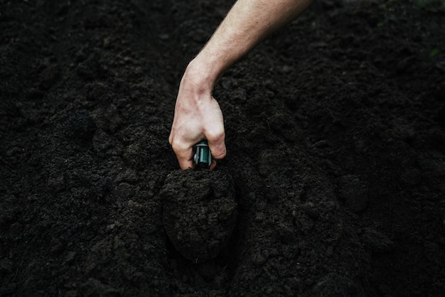 Um homem cava o solo com uma pá para plantar flores verdes ou ervas Detalhes do conceito de agricultura de outono ou primavera