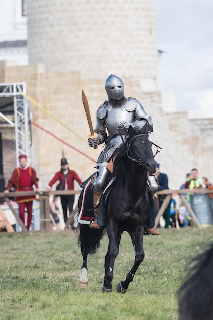 Um homem cavaleiro andando a cavalo segurando uma espada de madeira