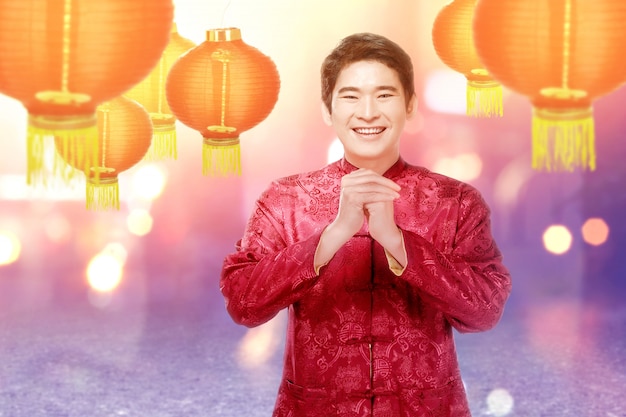 Um homem chinês asiático em um vestido cheongsam com gesto de parabéns