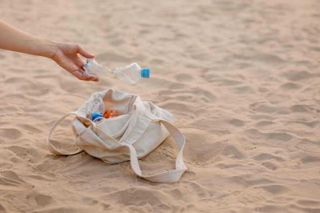 Um homem coleta garrafas plásticas e lixo na praia em um local público ecologicamente correto e cuidadoso