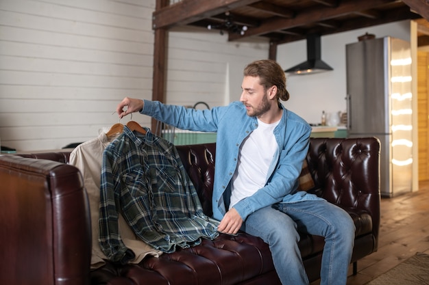 Um homem colocando suas camisas no sofá