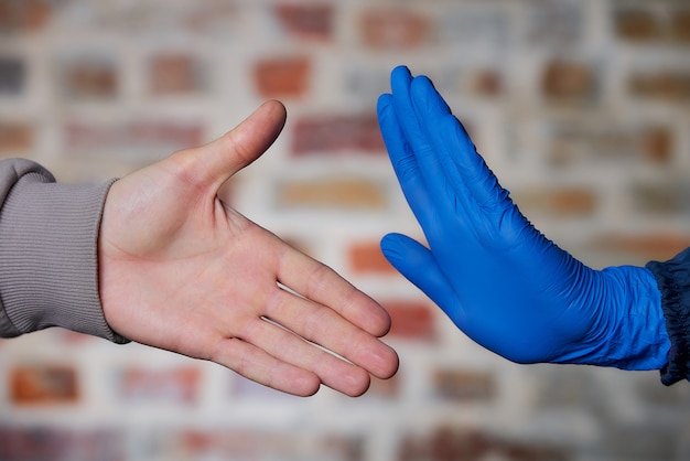 Foto um homem com a mão nua se oferece para cumprimentar uma mulher. uma mulher com a mão em uma luva médica descartável, parando-o para evitar a propagação do coronavírus (covid-19). ela não quer apertar as mãos.