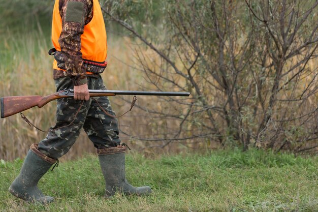 Um homem com armas e cães de caça rastreando o jogo