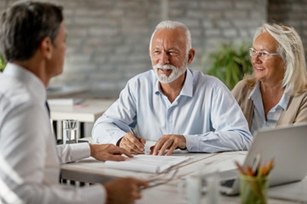 um homem com barba e bigode senta-se em uma mesa com um grupo de pessoas ao seu redor