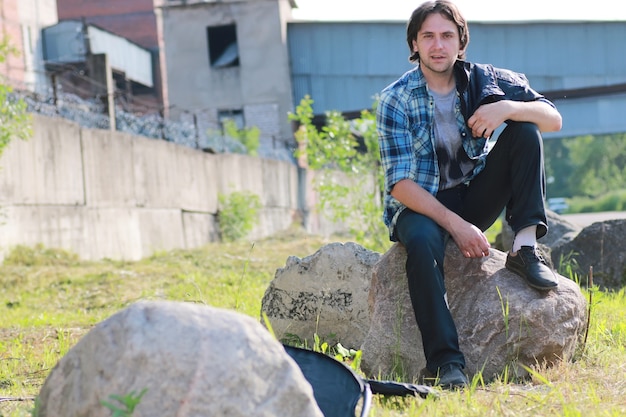 Um homem com barba e jeans fica na zona industrial