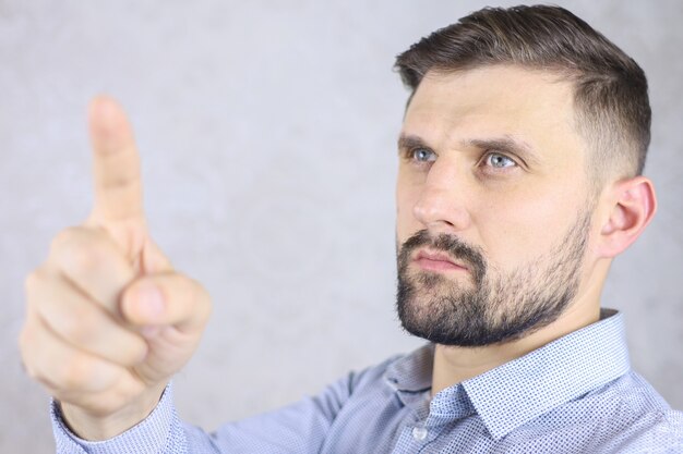 um homem com barba em uma camisa gesticula com os dedos