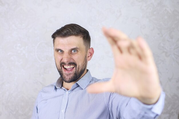 Foto um homem com barba em uma camisa gesticula com os dedos