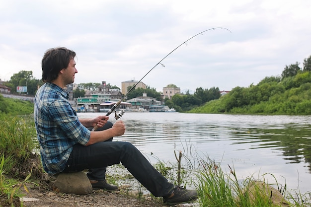 Um homem com barba está pescando para fiar no rio