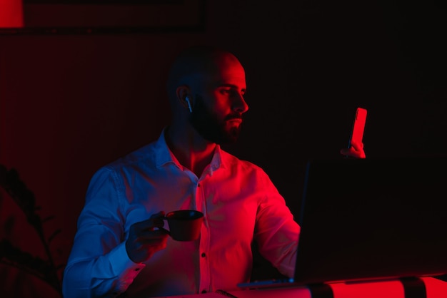 Um homem com barba está trabalhando remotamente em um laptop em casa