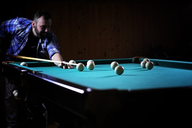 Um homem com barba joga um grande bilhar. festa na piscina de 12 pés. bilhar no jogo do clube para homens. um homem com um taco quebra a pirâmide.