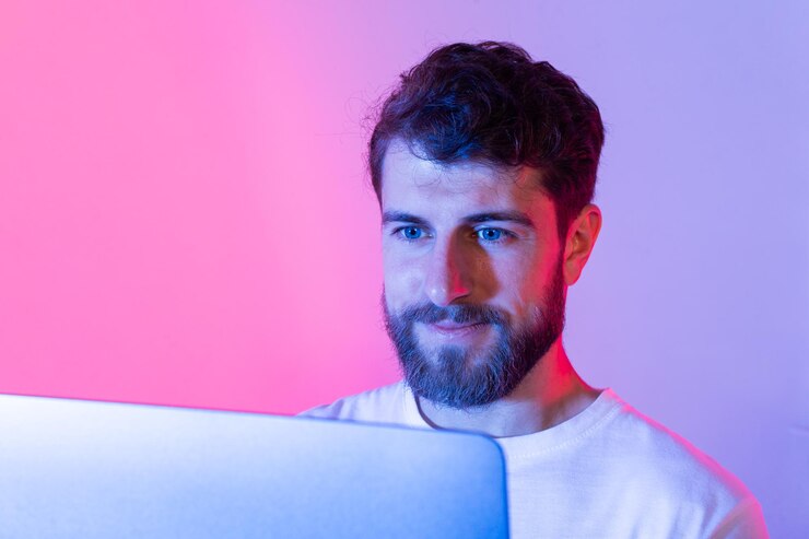 Foto um homem com barba senta-se na frente de um computador portátil digitando e navegando na internet ele está focado