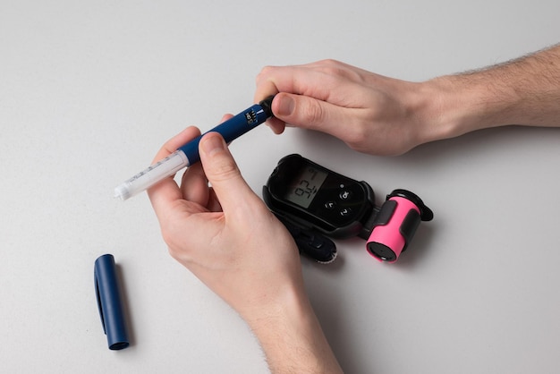 Um homem com diabetes mellitus obtém uma dose de insulina com uma seringa com uma caneta para aplicar uma injeção devido ao alto nível de açúcar no sangue.