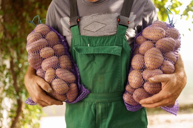 Um homem com dois sacos de batatas Agricultor carismático sênior segurando sacos com batatas