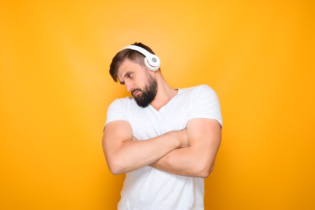 Um homem com fones de ouvido cruzou os braços na frente do peito e ouve música em fones de ouvido.