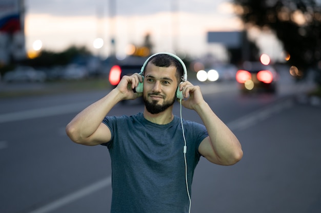 Um homem com fones de ouvido ouve música tarde da noite em uma rua da cidade