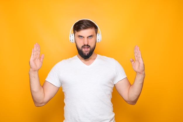 Um homem com fones de ouvido que ouve música mostra as mãos para o alto.