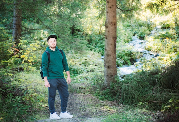 Um homem com mochila caminha na floresta de outono. Caminhada sozinha ao longo de caminhos na floresta de outono. Conceito de viagens.