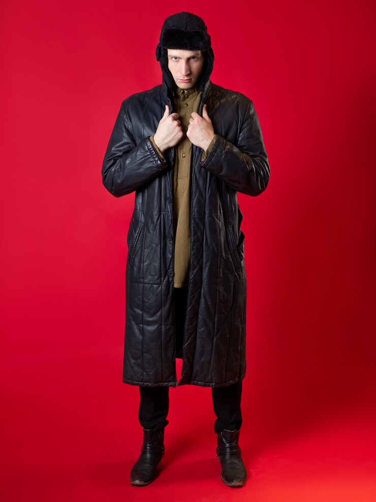 Foto um homem com roupas antiquadas e um chapéu com protetores de ouvido. retrato de estilo russo do pós-guerra em um fundo vermelho.